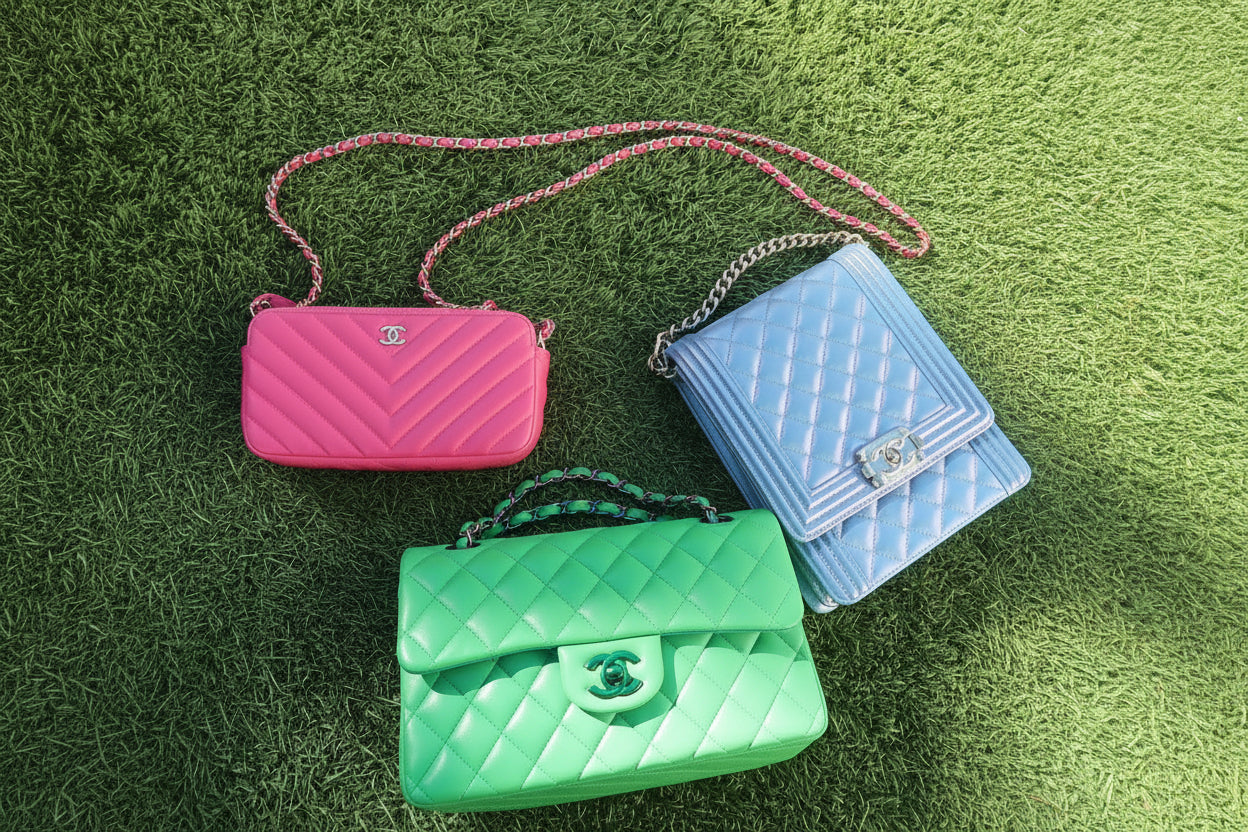 Three colorful handbags (pink, blue, green) on a grassy surface